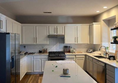 Modern kitchen with white cabinets, stainless steel appliances, and items scattered on the island counter.