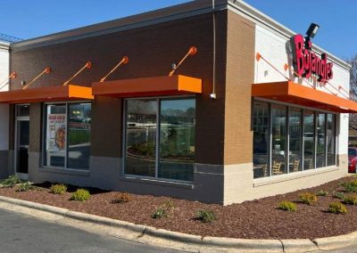 A Bojangles restaurant with orange awnings and large windows on a sunny day.