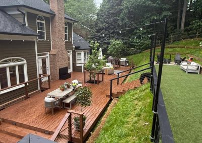 A spacious backyard with a wooden deck, outdoor furniture, and a grassy area surrounded by trees.