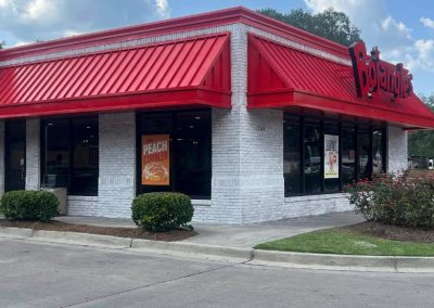 A Bojangles restaurant with red accents, large windows, and a sign advertising peach cobbler.