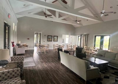 Spacious lounge with sofas, armchairs, tables, and large windows letting in natural light.