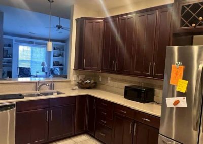 Modern kitchen with dark wood cabinets, stainless steel appliances, and a fridge with notes attached.